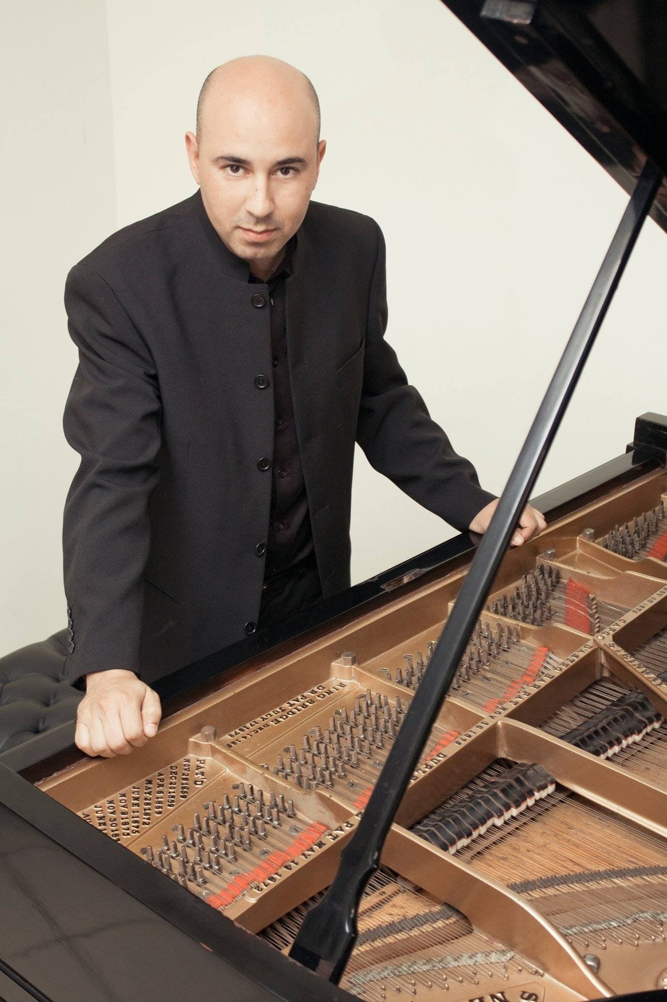 Juan Estay Santander standing behind a grand piano