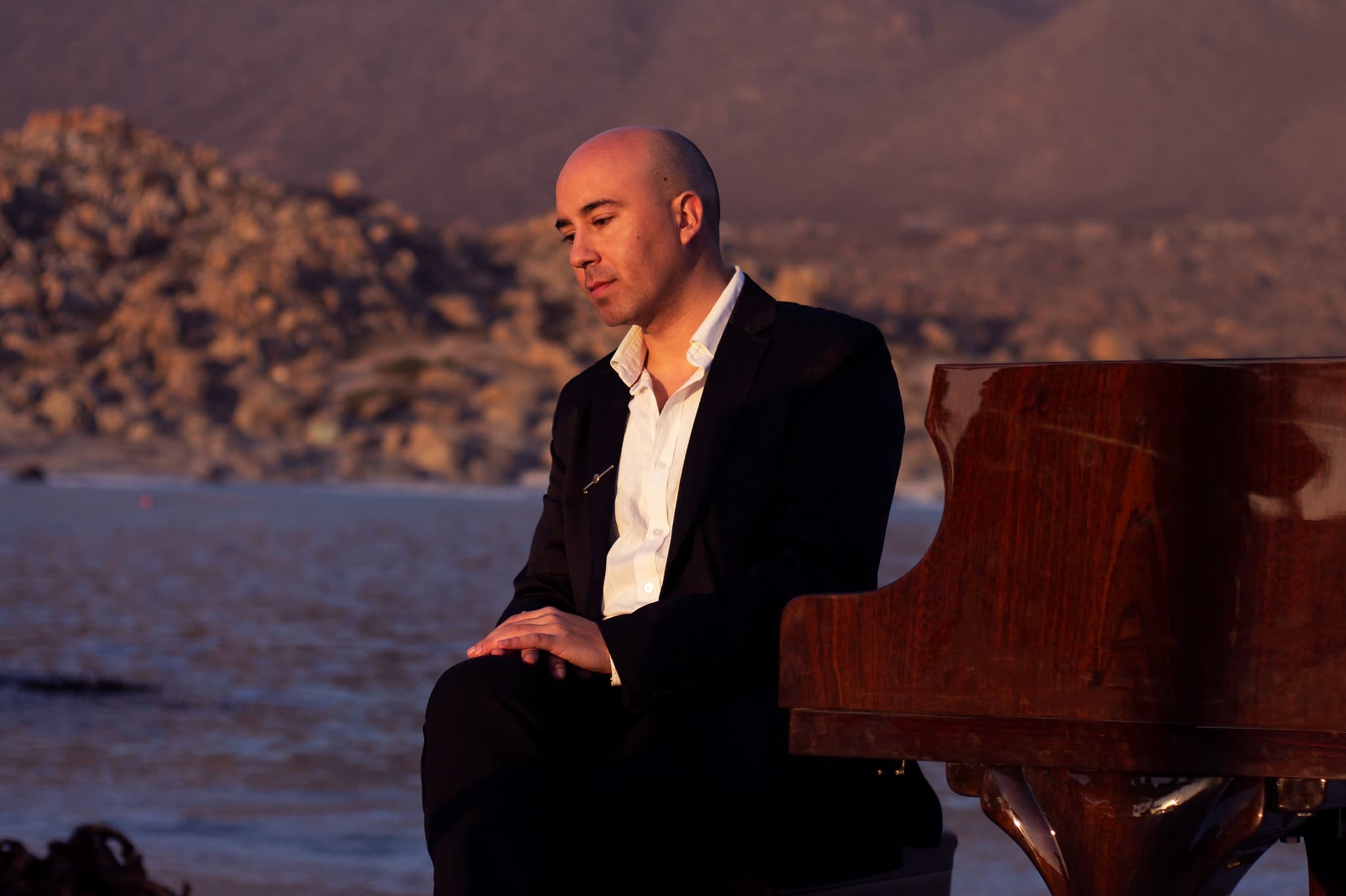 Juan Estay Santander at the piano by the sea at sunset